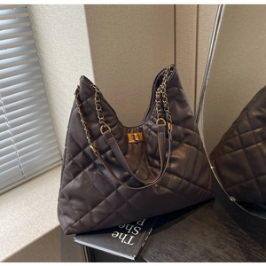 Detail of dark brown quilted leather tote with gold twist lock and chain strap texture