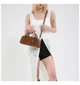 Detailed view of the dark brown Boston bag featuring golden hardware and round handles