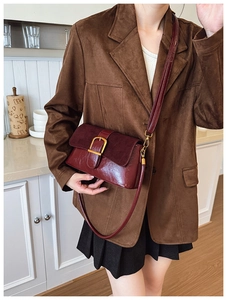 Detail of burgundy vintage crossbody bag featuring glossy leather and golden buckle