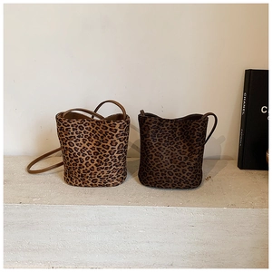 Detail of leopard print bucket bags with leather straps and minimalist curved opening