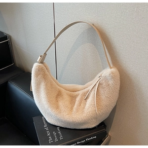 Detail view of plush beige faux fur hobo bag with sleek leather strap on black books