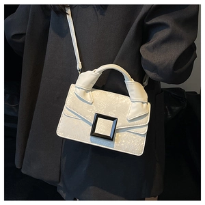 Detailed view of cream faux snakeskin texture on a handbag with chic black buckle