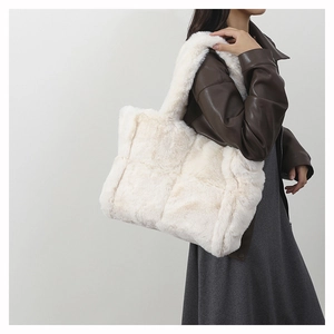 Detail of a white faux fur patchwork tote bag worn with a brown leather jacket