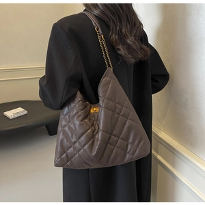 Detail of deep brown quilted leather bag with gold metal twist lock and chain strap