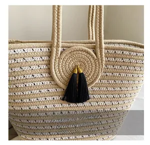 Detailed close-up of handmade woven handbag with black tassel and gold metal hardware