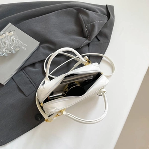 White mini Boston bag showing spacious interior with phone, lipstick and makeup items