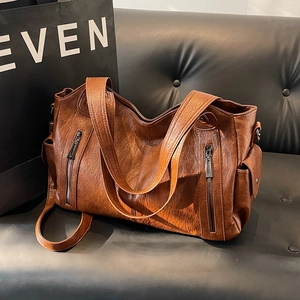 Brown vintage faux leather tote bag with multi-pocket design on a leather sofa