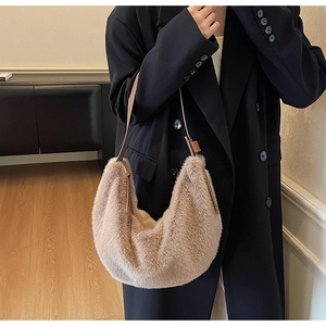 Détail d'un sac demi-lune en peluche crème avec un manteau noir oversize élégant