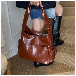 Detail of dark brown glossy leather shoulder bag with vintage silver rivet studs