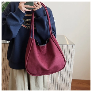 Detail showing the burgundy suede shoulder bag with its premium matte finish texture