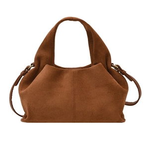 Brown suede tote bag with vertical stitching and bronze hardware in a minimalist design