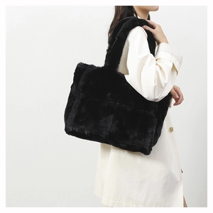 Furry black tote bag shown on a model's shoulder with minimalist cream trench coat outfit