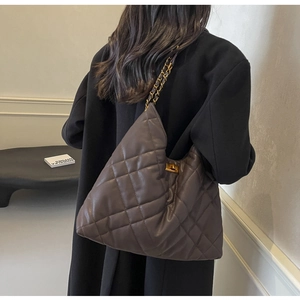 Detail of taupe quilted leather bag with large diamond stitching and gold metal chain strap
