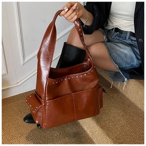 Detail view of vintage brown tote bag featuring silver studs and functional side pockets