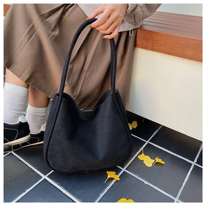 Close-up of minimalist black suede hobo bag shown in an autumnal outdoor lifestyle setting