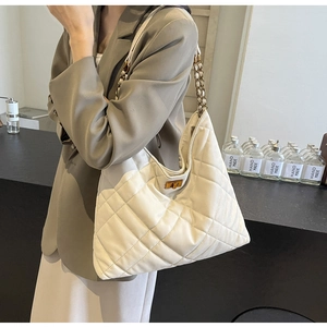 Detail of off-white quilted hobo bag featuring a gold twist lock and metal chain strap