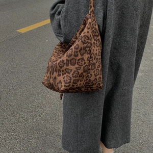 Large leopard print hobo bag in soft texture carried over a grey herringbone wool coat