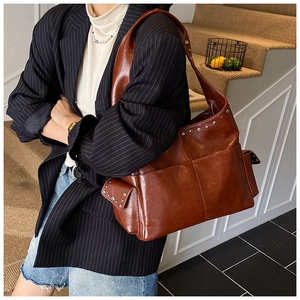 Detail of vintage brown tote bag featuring rivet studs and premium oily leather texture