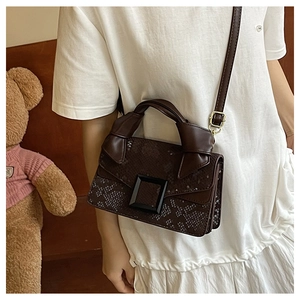 Detail of dark brown snakeskin texture handbag with buckle and adjustable strap