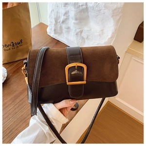 Detail of vintage patchwork shoulder bag featuring a gold horseshoe buckle and suede leather