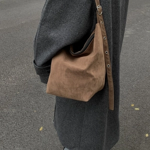 Brown suede large hobo bag with adjustable eyelet shoulder strap worn by a model