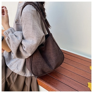 Detail of the soft brown suede shoulder bag featuring a spacious minimalist retro design