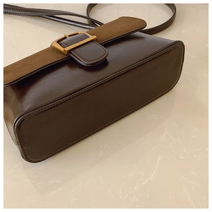 Detail of dark brown leather shoulder bag with suede stitching and vintage gold buckle