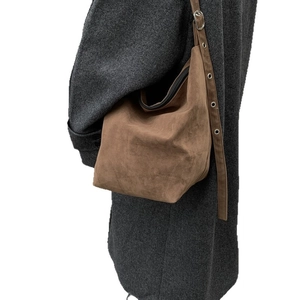 Brown suede hobo bag with adjustable eyelet strap shown on model over tweed coat