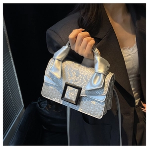 Silver snake pattern handbag with black matte buckle and twist handle detail on model