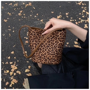 Outdoor shot of leopard print bucket bag with brown handles on autumn leaf road