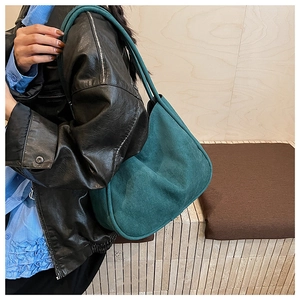 Detail of dark green oversized faux suede tote bag worn as a crossbody shoulder bag