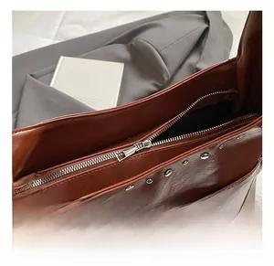 Detail shot of silver rivets and smooth zipper closure on brown leather tote bag