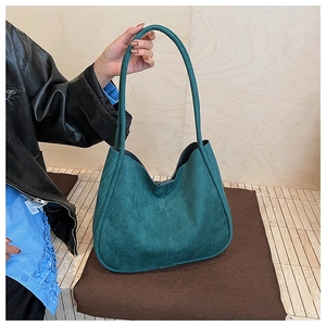 Detail view of large dark green faux suede hobo tote bag held by model