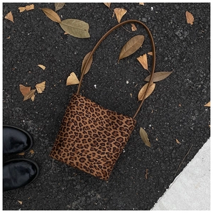 Top-down view of a leopard print bucket bag on a street with leaves for style context
