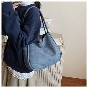 Close-up of matte grey-blue hobo bag showing premium suede texture and long shoulder straps