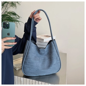 Detail of blue faux suede tote bag featuring slim shoulder straps and large capacity