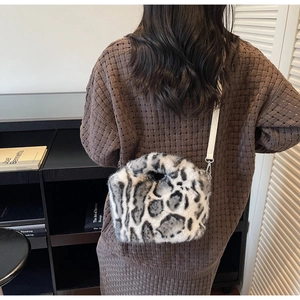 Detailed close-up of a leopard print faux fur crossbody bag on a knit sweater shoulder