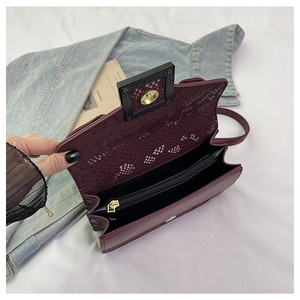 Detail view of the purple snakeskin textured shoulder bag interior with magnetic closure