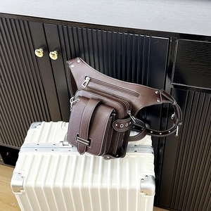 Sac banane rétro en cuir marron foncé avec plusieurs poches sur une valise