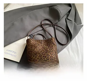 Detail of leopard print bucket bag with leather handles on a grey suit and white bedding