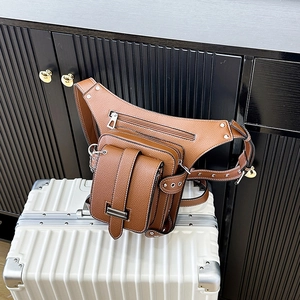 Sac banane vintage en cuir marron avec plusieurs poches sur une valise blanche