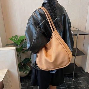 Detail of minimalist large capacity hobo bag in camel suede with elegant slouchy drape