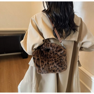 Detail of leopard print faux fur crossbody bag with leather strap on a model wearing a coat