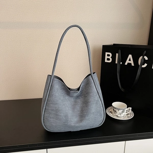 Detail of light gray suede tote bag on dark surface with elegant minimalist accessories