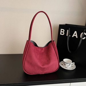 Detailed texture of burgundy suede shoulder bag with minimalist curved silhouette