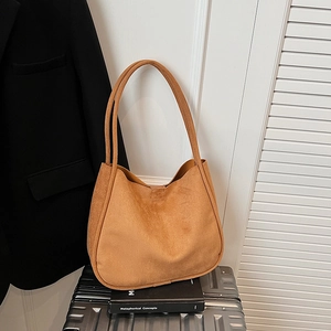 Close-up of a brown suede hobo bag styled with a suitcase for a fashionable travel look
