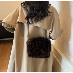 Detail of leopard print faux fur crossbody bag with leather strap on beige trench coat