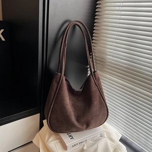 Detail of dark brown suede hobo bag with minimalist texture and long handles