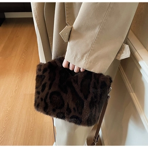 Detail of plush leopard print faux fur handbag with dark brown leather shoulder strap