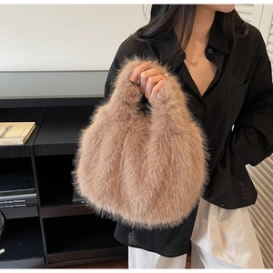 Close-up of model holding the khaki faux fox fur handbag with plush texture and handle